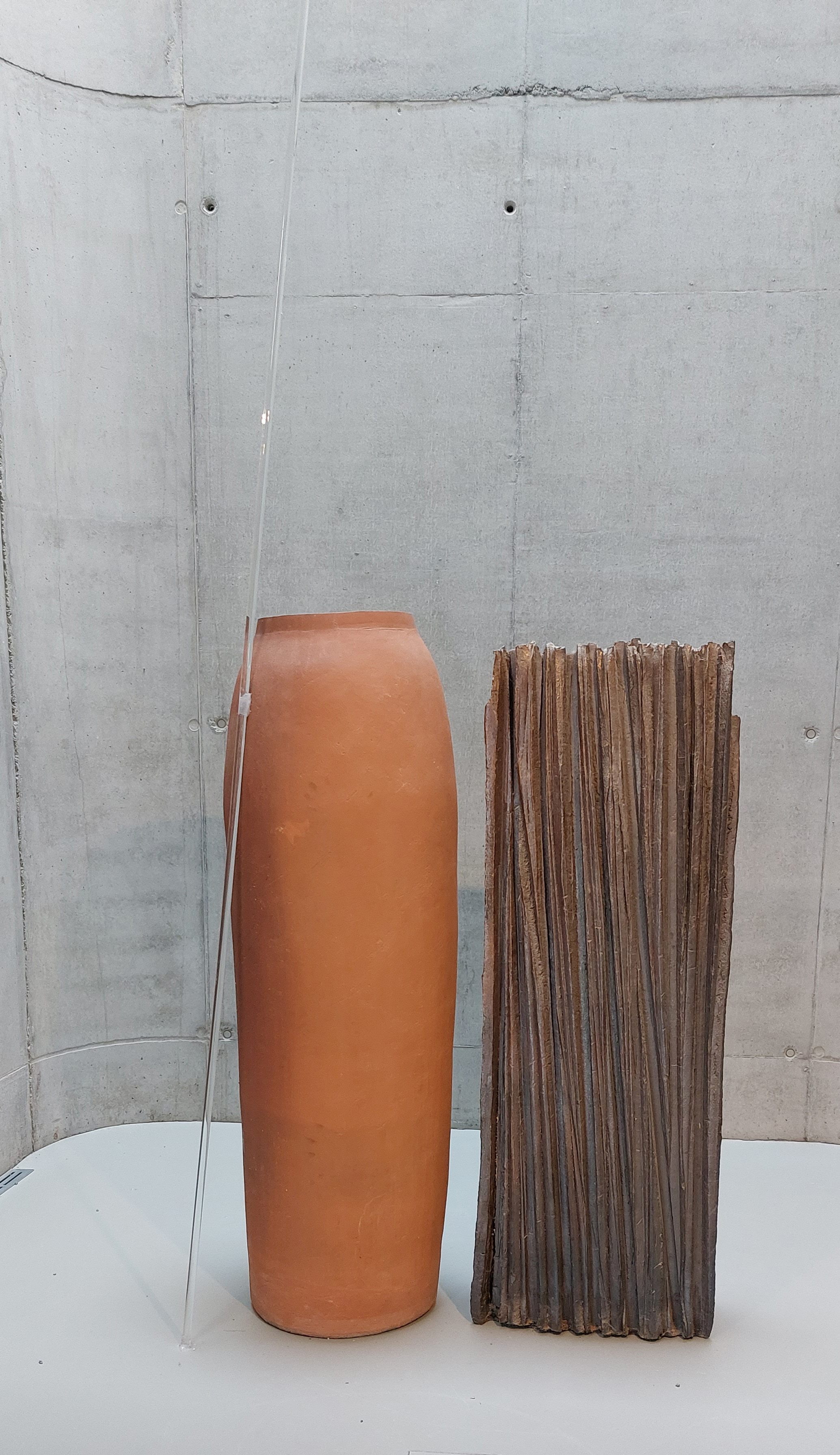 Daniel Pontoreau, Sans Titre, 1990, ensemble de 3 pièces monumentales : une amphore couleur rouge brique, un colonne carrée striée de lignes verticales sur toute sa longueur, posés côte à côte, 1 tige de verre posée contre l'amphore