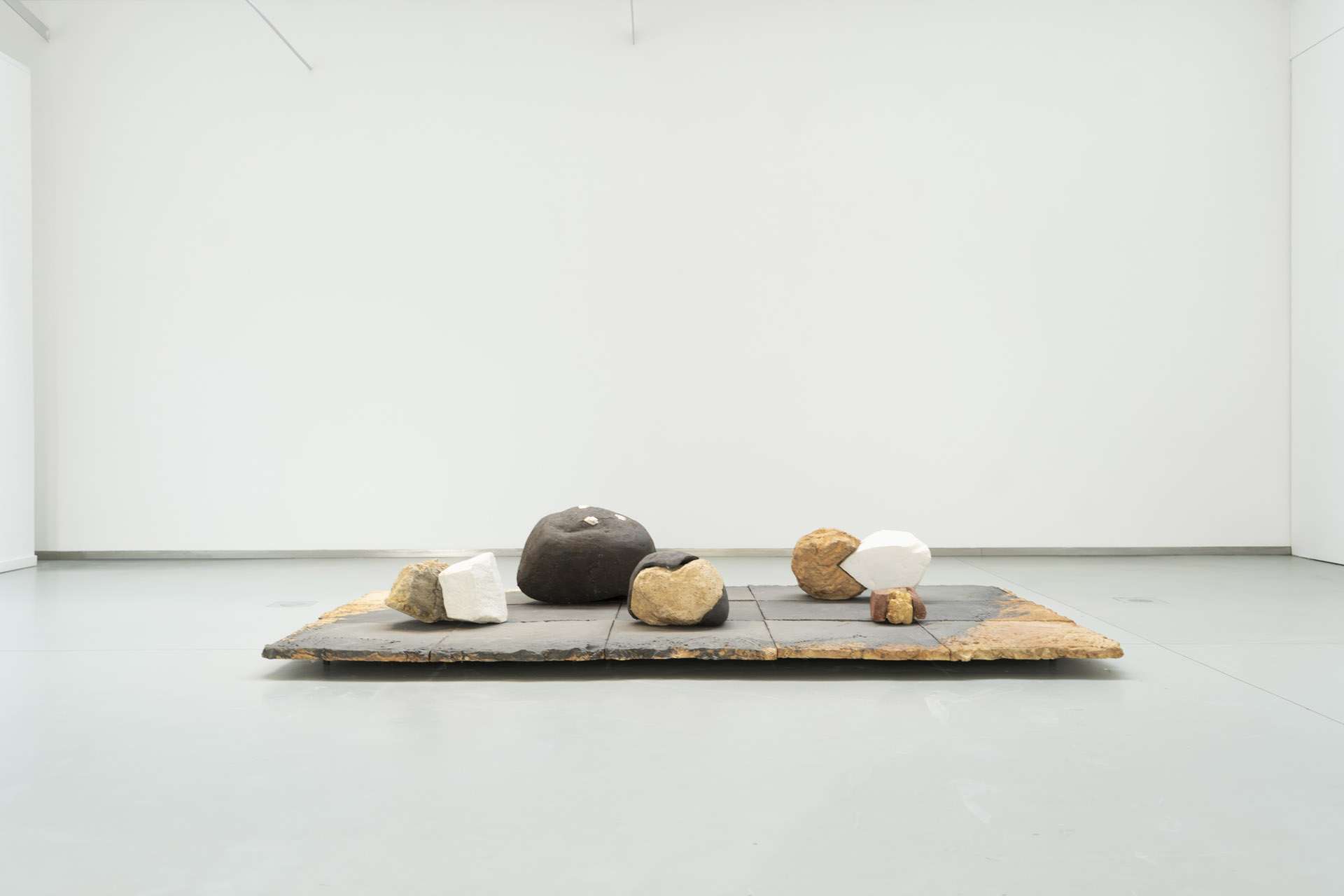 Daniel Pontoreau, Five easy Pieces, 2016, sur un dallage en céramique, 5 pièces hybrides mêlant céramique et porcelaine blanche de formes diverses, exposition Avant le Paysage, Keramis, 2023, La Louvière, Belgique, Boombartstic Art Magazine