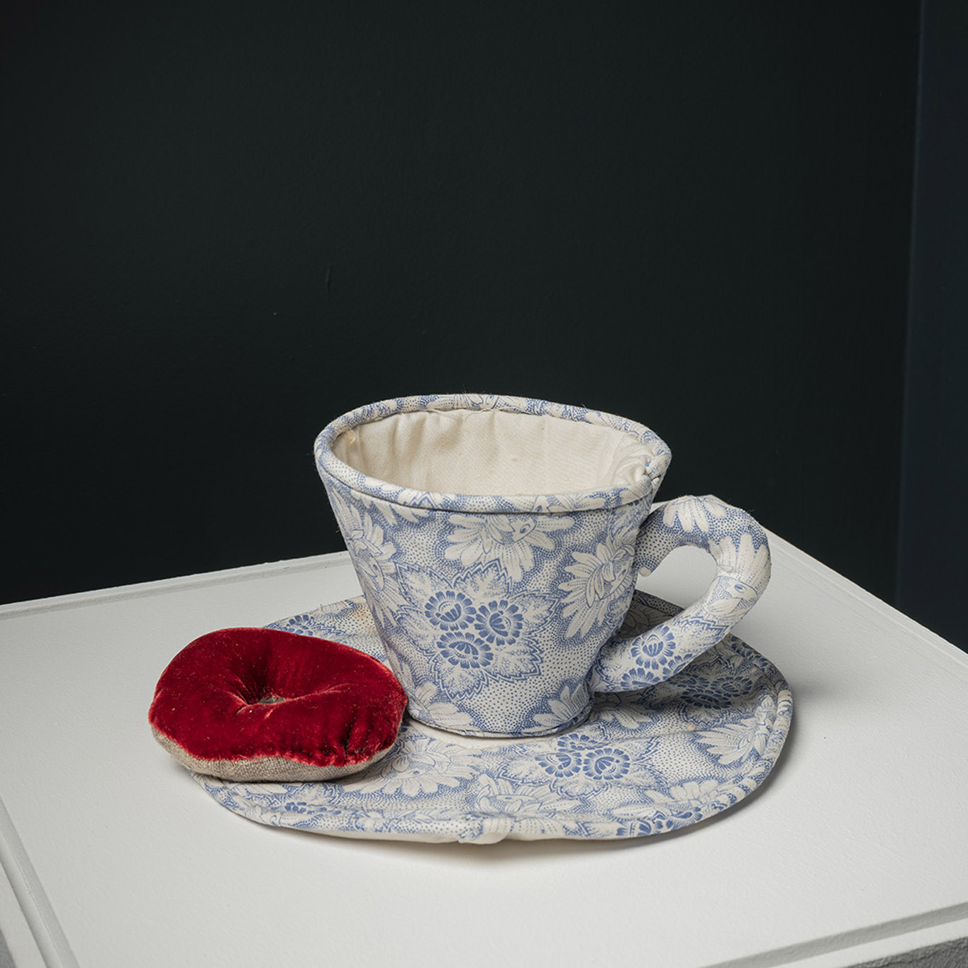 Jann Haworth & Cindy Wright, ensemble en tissu, une tasse et sa soucoupe avec motifs Delft bleus, beignet en tissu velours brun caramel posé sur la soucoupe, exposition En Regard, Le Delta, Namur, 2023, Boombartstic Art Magazine