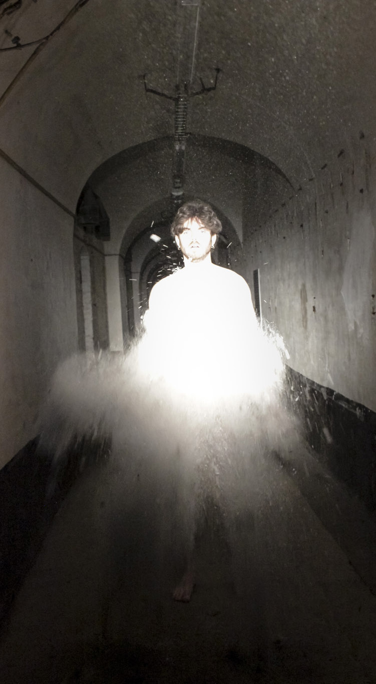 Juan Paparella, portrait d'un homme qui se dissout dans la lumière blanche, photo prise dans le couloir d'une ancienne caserne, exposition En Regard, Le Delta, Namur, 2023